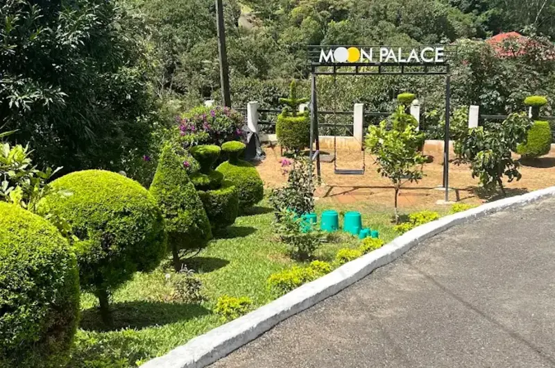 Landscaped garden pathway with manicured hedges leading to Moon Palace Kuttikanam entrance