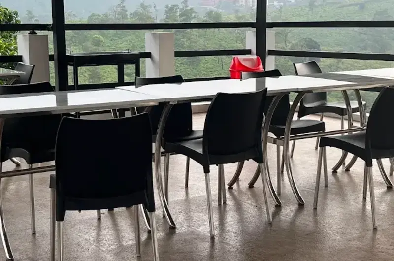 Shaded indoor dining hall with dining tables and wall-mounted television at Moon Palace Kuttikanam