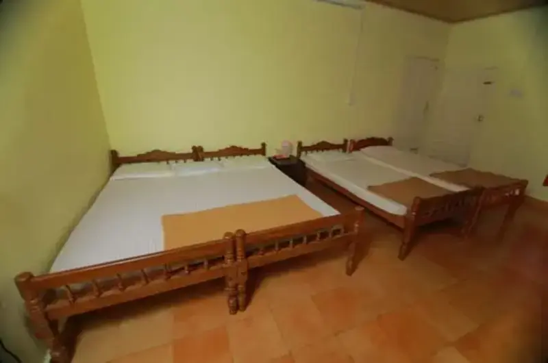 Spacious guest room featuring twin double beds, wooden headboards, and yellow walls at Himaharsham Homestay