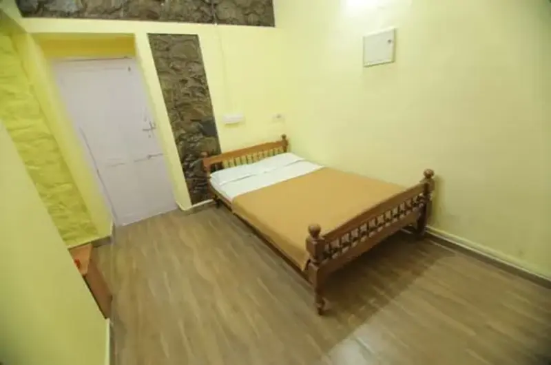 Cozy guest room bedroom featuring a single wooden bed, warm lighting, and simple decor