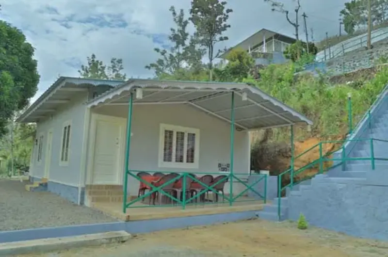 Front view of cottage property with sloping roof and green lawn at Himaharsham Homestay Vagamon