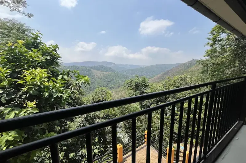 Private guest room balcony with black railings offering scenic forest and mountain views