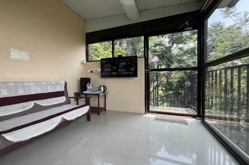 Spacious guest suite interior featuring sofa seating, television, and glass wall views of nature