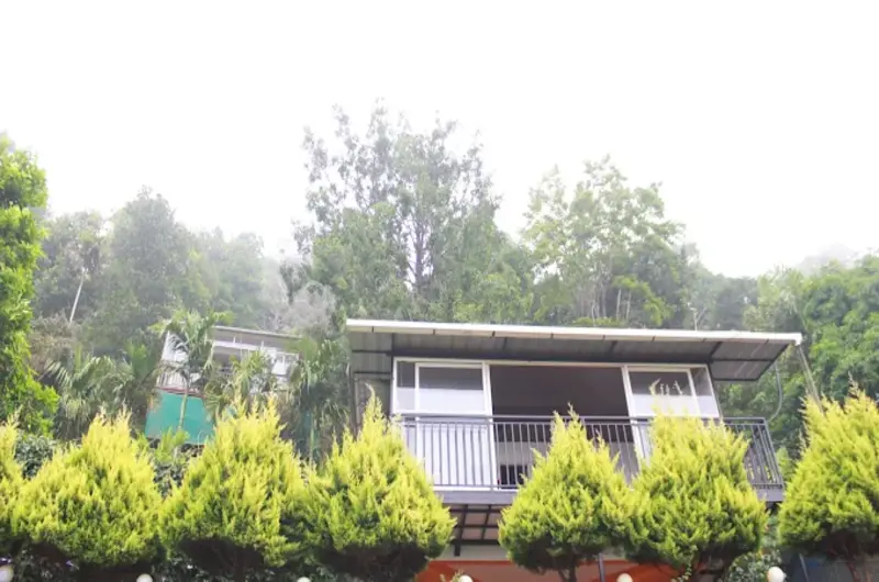 Exterior view of modern hill cottage with sloped roof and potted garden plants at Theeram Agro Farm Hill Resort