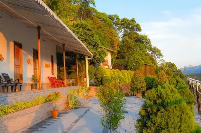 Cottage guest rooms with outdoor porch seating and garden hillside view at Theeram Agro Farm Hill Resort Vagamon