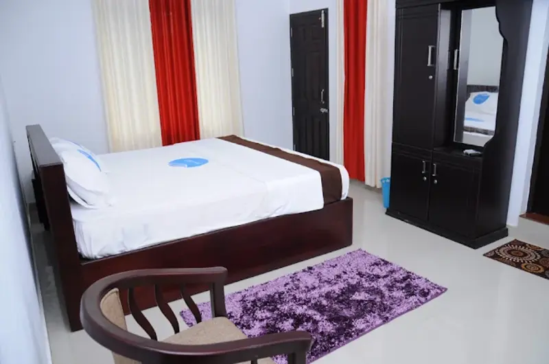 Cozy guest room bedroom featuring a double bed, bedside seating nook, and window drapes at Snow White Residency