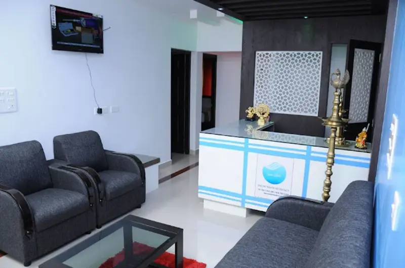 Hotel reception lounge featuring modern counter desk, black leather sofas, and blue decorative wall at Snow White Residency