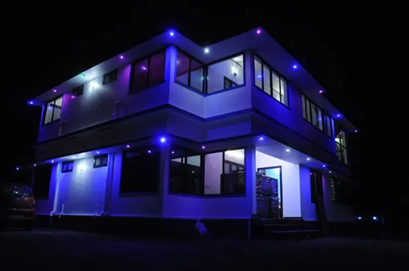 Multi-story hotel building illuminated with blue ambient exterior lights at night at Snow White Residency Vagamon