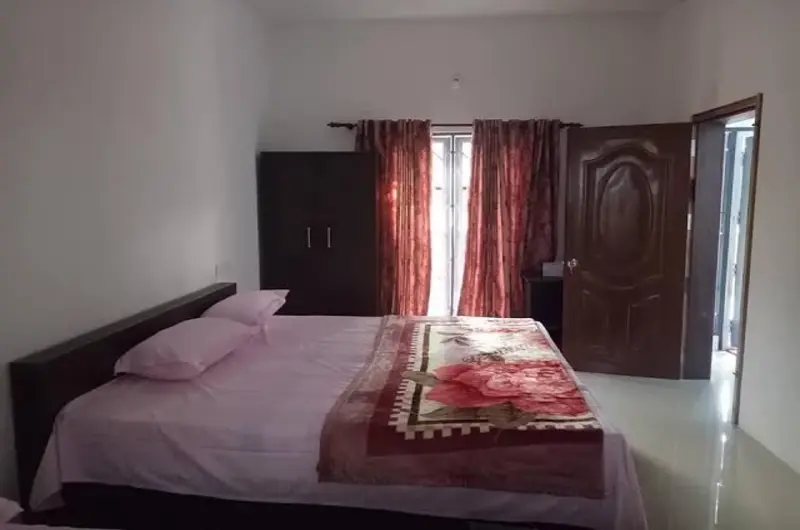 Cozy villa guest bedroom featuring a comfortable double bed, dark drapes, and warm ambient lighting