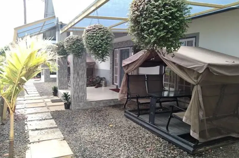 Paved outdoor garden patio with lounge seating surrounded by greenery at Eagle Rock Holiday Villas Peerumade