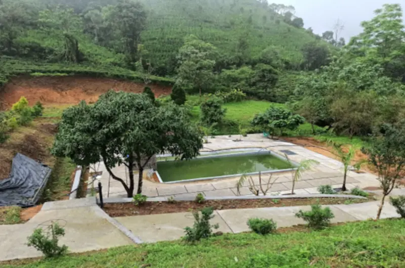 Outdoor swimming pool deck overlooking surrounding misty hills and greenery at Vagamon Hues