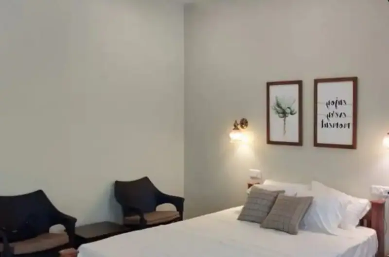 Spacious guest suite featuring a king-size bed, bedside chairs, and warm ambient lighting