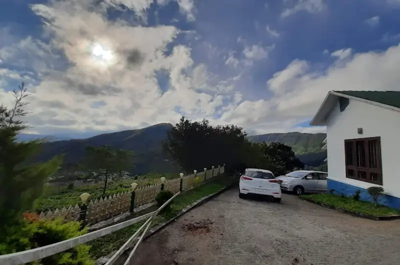 Illuminated white homestay building set along paved yard against mountain hills at Pine View Homestay