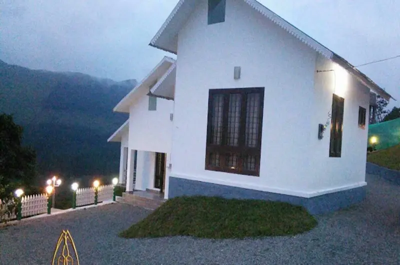 Side exterior facade of white cottage structure with wall lights at Pine View Homestay Vagamon
