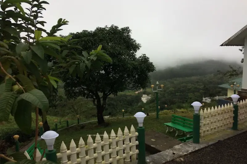 Landscaped garden boundary wall overlooking misty green valleys and hills in Vagamon