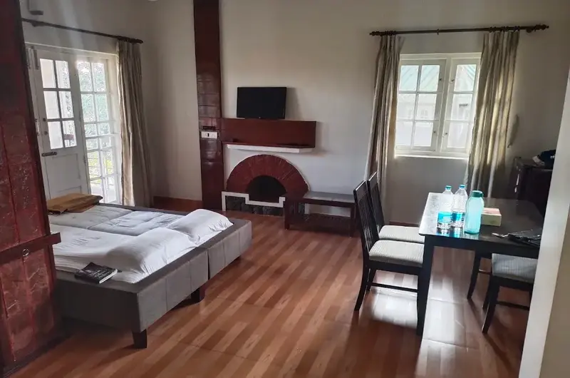 Spacious cottage guest room interior featuring a comfortable double bed, wooden furniture, and dining table at Orion County Vagamon