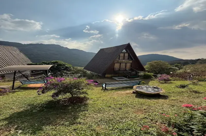 Wooden resort cottages with lawn seating set against misty green hills at JMount Vagamon Resort