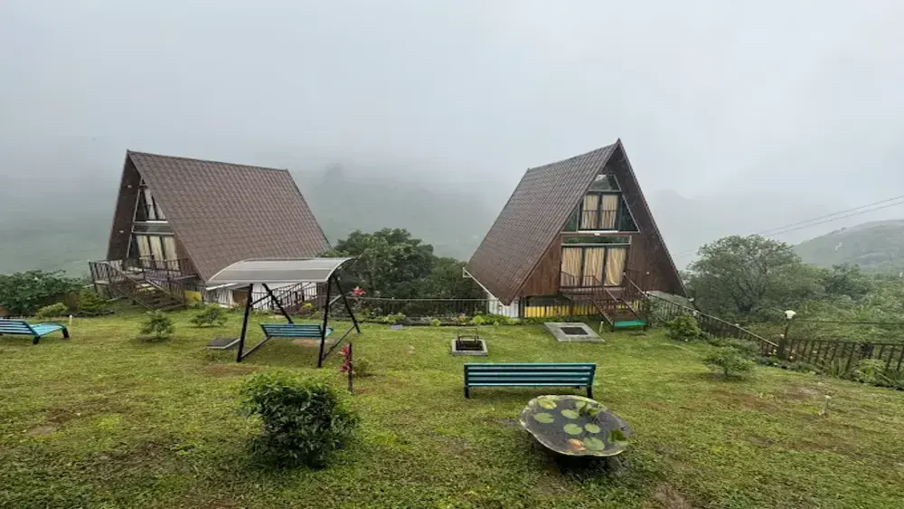 Exterior view of modern dark wooden A-frame cottages surrounded by green hills at JMount Vagamon Resort