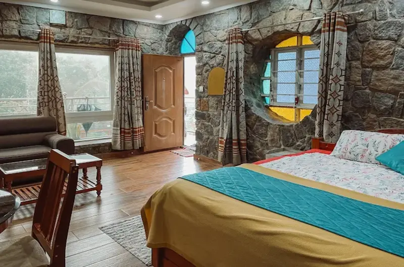Resort guest suite with exposed stone masonry wall, king bed, and seating area at Vaga Copper Castle