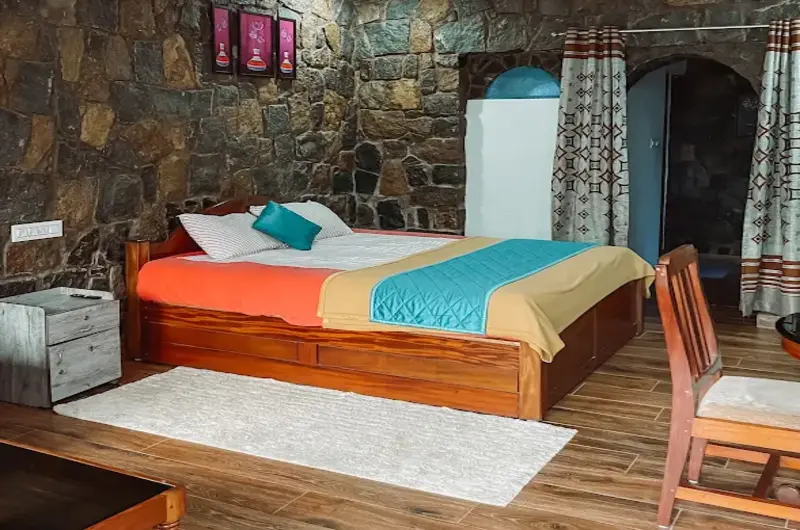 Cozy resort bedroom featuring stone wall masonry, twin double beds, and warm lighting at Vaga Copper Castle