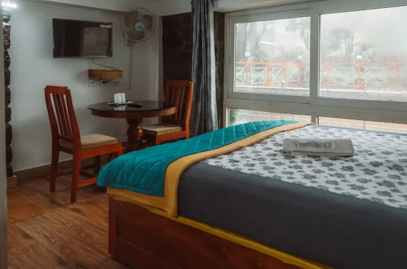 Spacious bedroom suite featuring a king-size bed with colorful runner and window view at Vaga Copper Castle