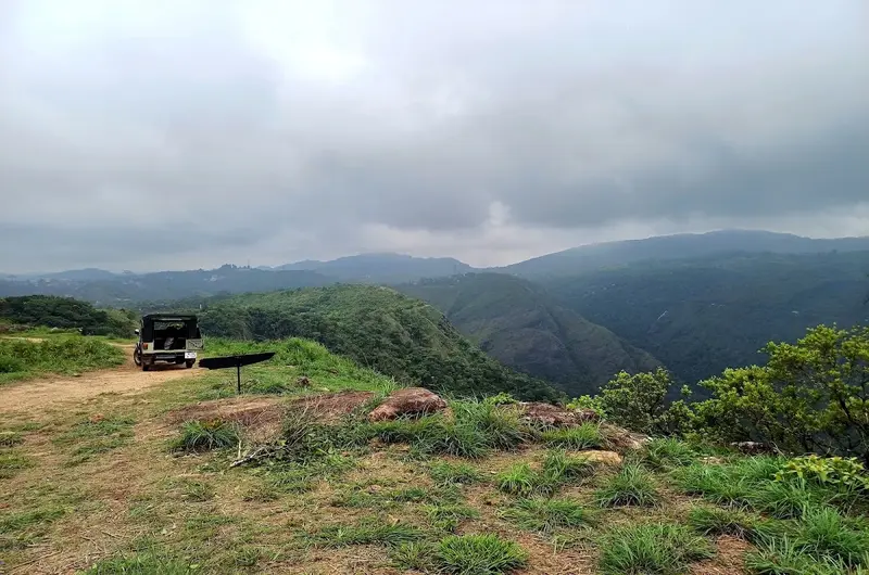 4x4 off-road jeep parked on a high mountain peak overlooking rolling hills at Vagamon Heights