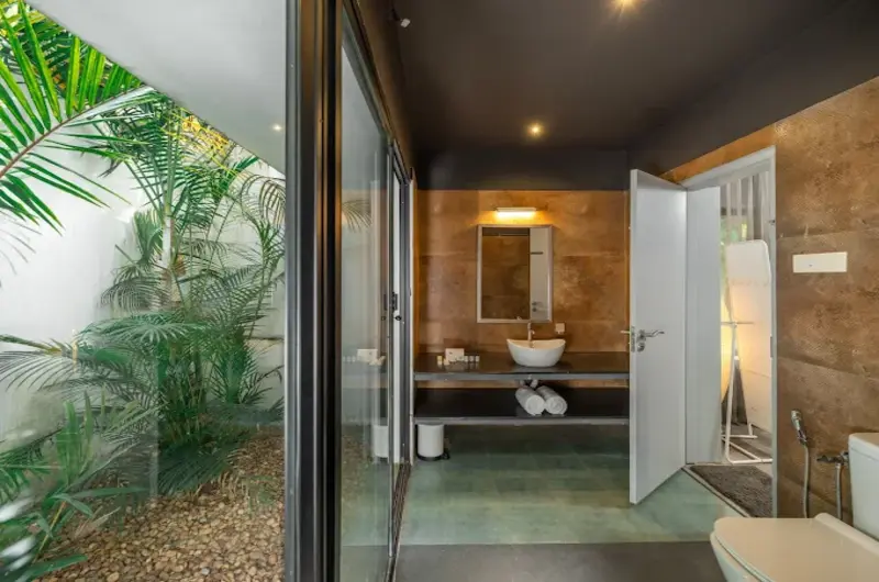 Paved outdoor garden courtyard patio featuring comfortable lounge chairs surrounded by lush green foliage