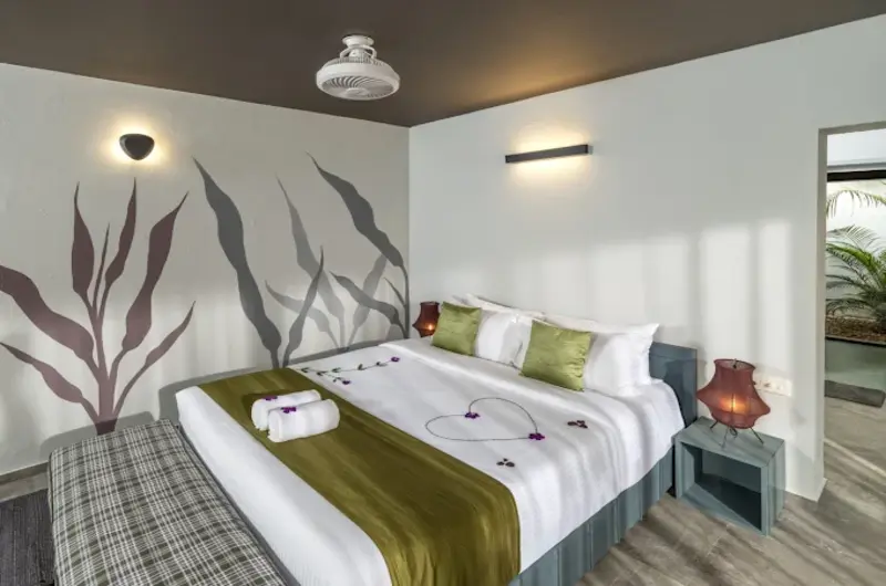 Cozy resort bedroom featuring a king bed with green leaf wall mural and modern lighting