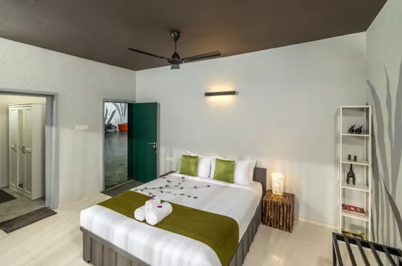 Spacious guest bedroom suite featuring a king bed decorated with green towel swan art and warm ambient lighting