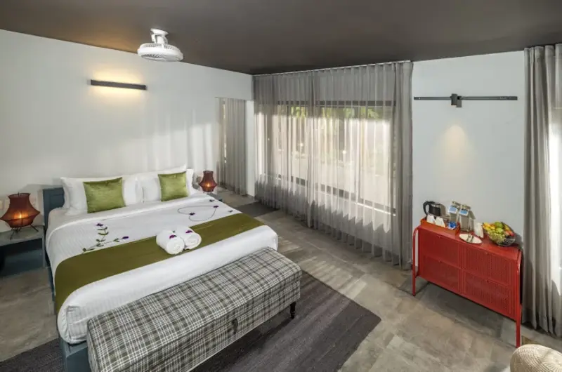 Deluxe resort guest room with king bed, plush bedding, and floor-to-ceiling glass doors opening to a balcony