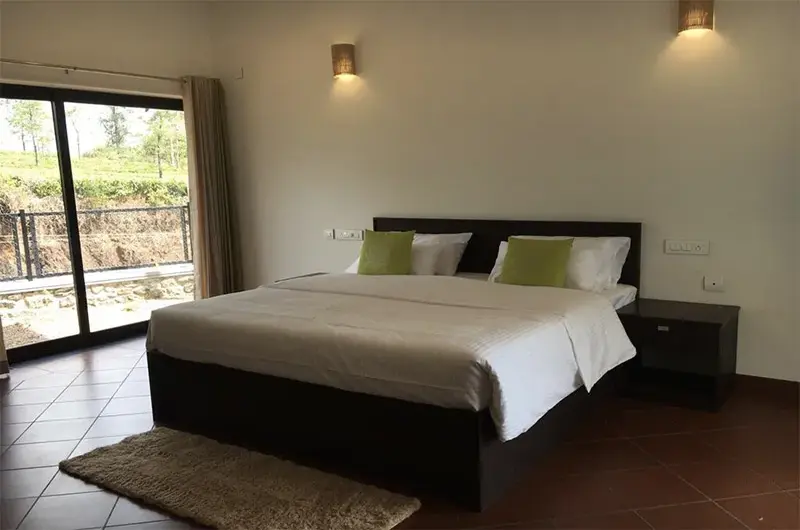 Luxury bedroom interior featuring warm lighting, plush double bed, and large window views at Beyond Pines Vagamon
