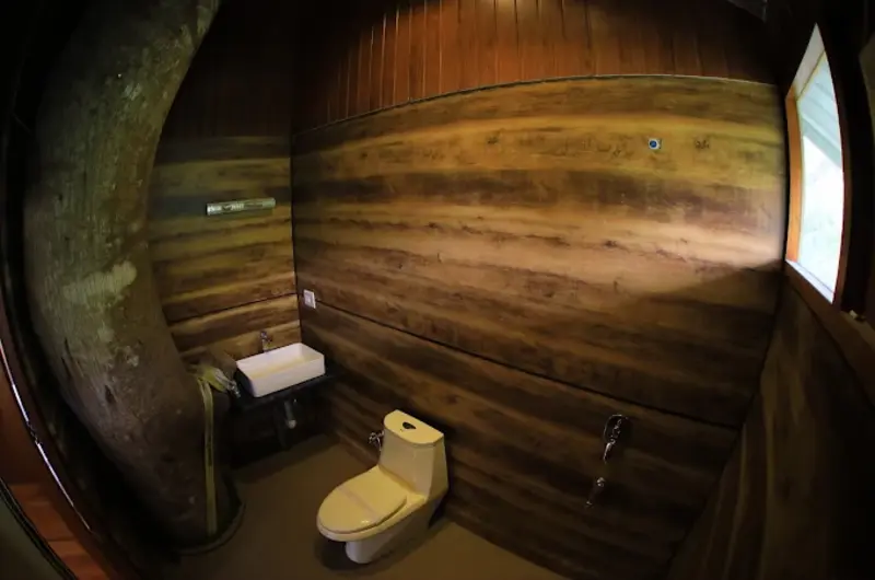 Clean wooden cottage bathroom interior with toilet and vanity mirror at Orma Farm Resorts Vagamon