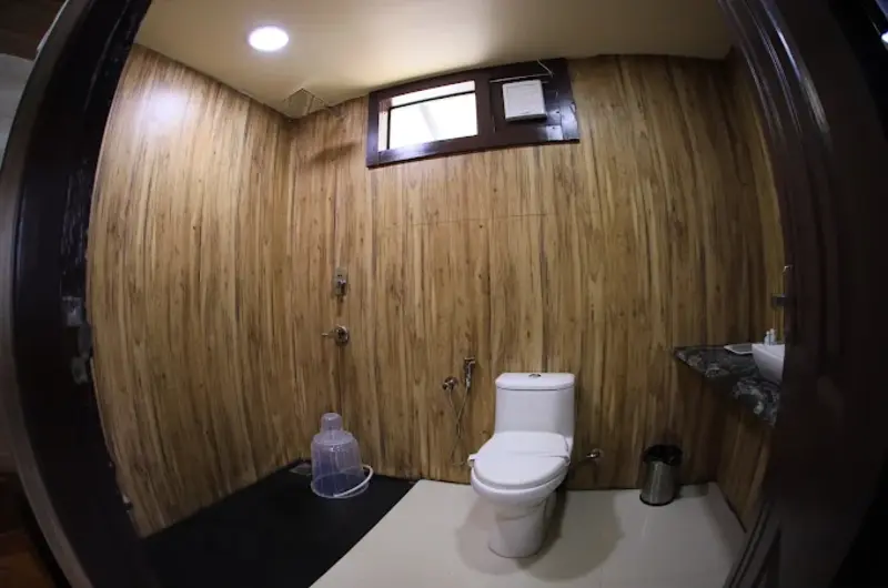 Modern tiled attached bathroom with wooden paneling and washbasin at Orma Farm Resorts Vagamon