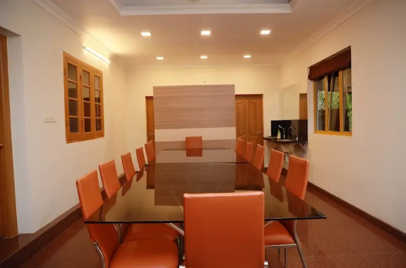Spacious wooden room lounge interior with orange armchairs and dining table at Orma Farm Resorts Vagamon