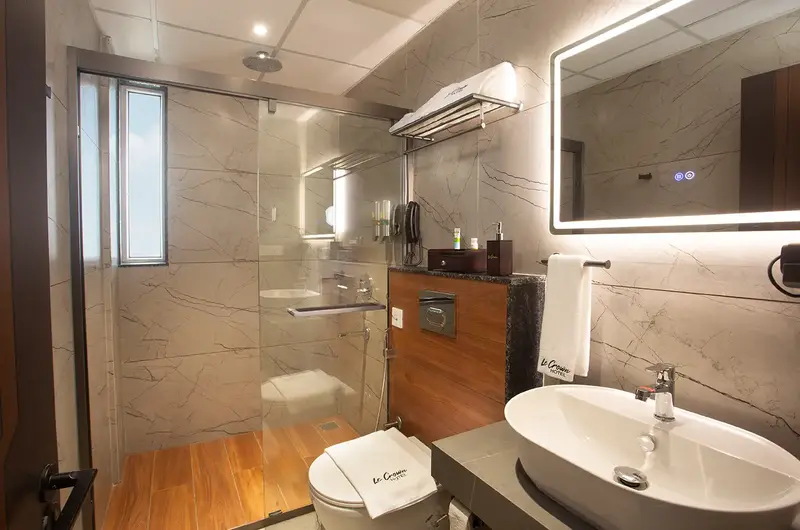 Modern attached bathroom with vanity sink mirror and stylish lighting at Le Crown Hotel Vagamon