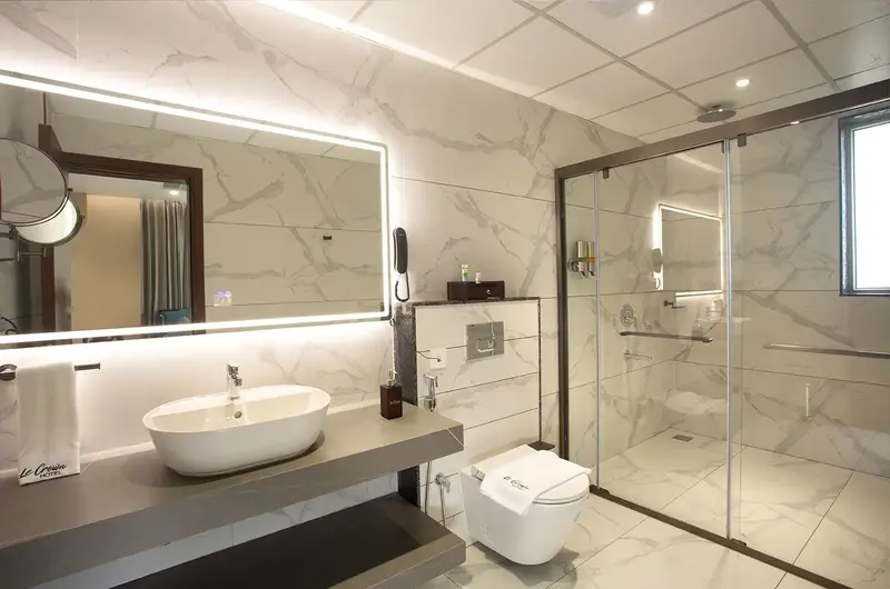 Clean modern bathroom featuring glass shower enclosure and vanity sink at Le Crown Hotel Vagamon