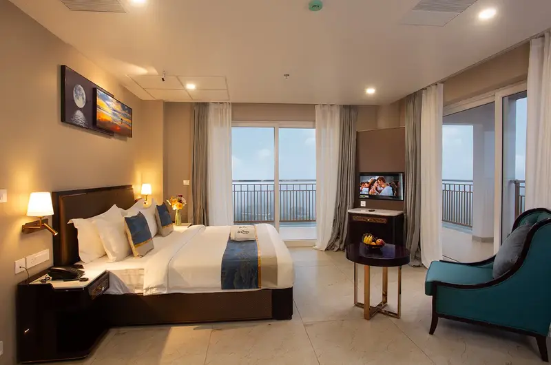 Spacious deluxe guest room with plush king bed and seating near balcony at Le Crown Hotel Vagamon