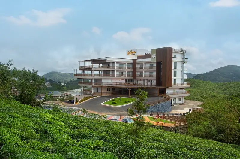 Modern hotel building perched on lush green hill at Le Crown Hotel Vagamon