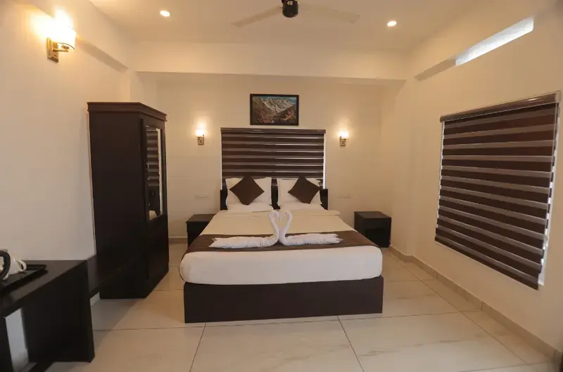 Elegantly furnished luxury bedroom with dark wood decor at Himasailam Resort Vagamon