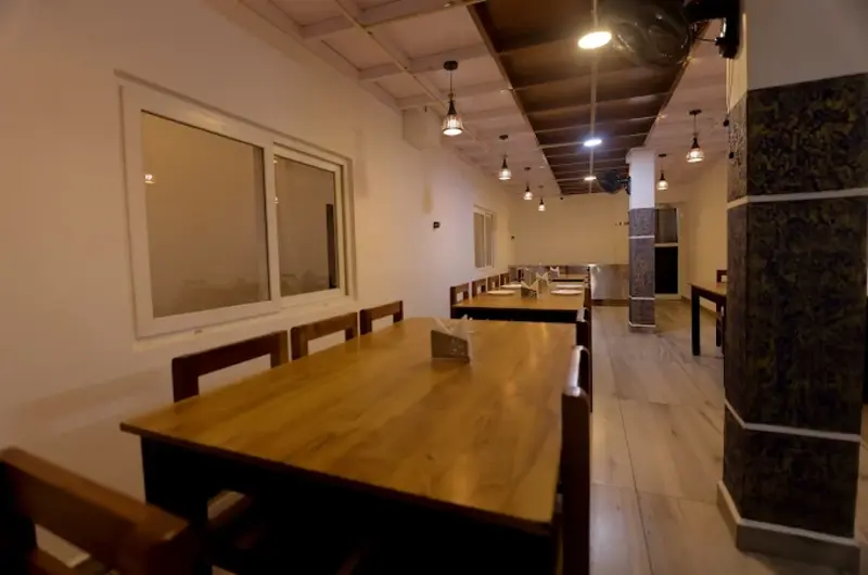 Wooden dining tables and chairs inside the resort restaurant at Himasailam Resort Vagamon