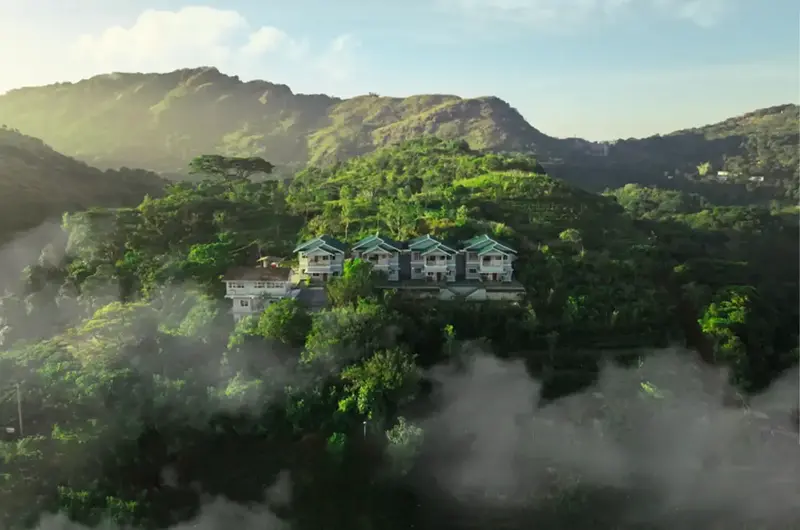 Aerial view of lush green mountain hills and valleys surrounding The Autumn by Maat Hotels Vagamon