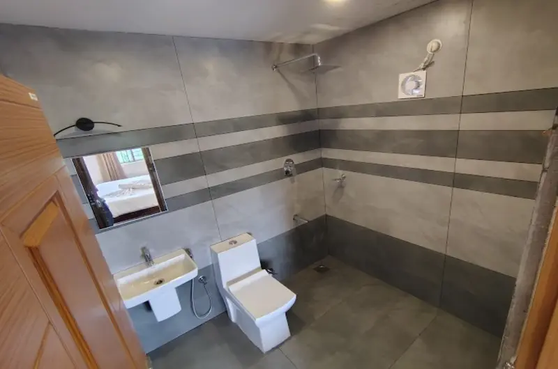 Clean modern attached bathroom with tiled walls and premium fixtures at The Autumn by Maat Hotels Vagamon