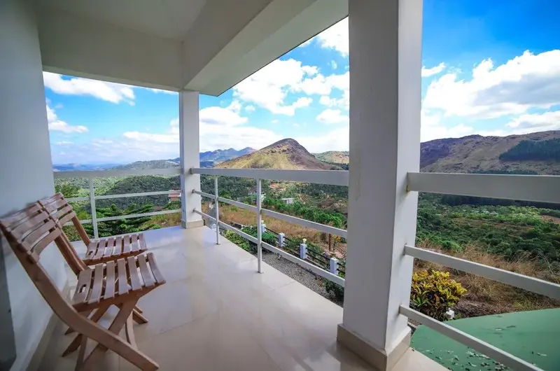 Private balcony deck with outdoor chairs overlooking scenic hills at The Nest Homestay Vagamon