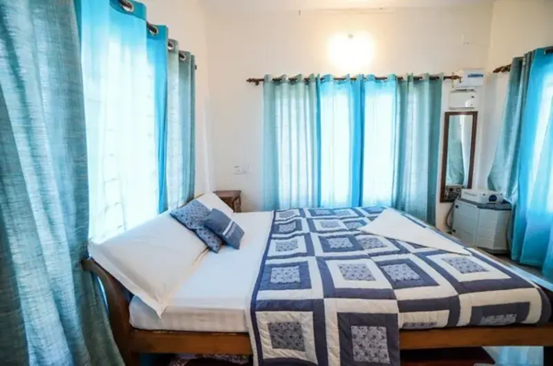 Cozy homestay guest room featuring double bed with blue curtains at The Nest Homestay Vagamon