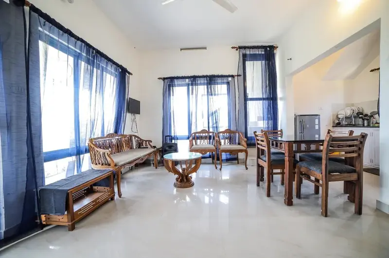 Spacious living room and wooden dining space with large windows at The Nest Homestay Vagamon