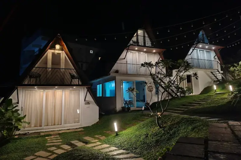 Illuminated A-frame cottages at night at Trip Mount resort Vagamon