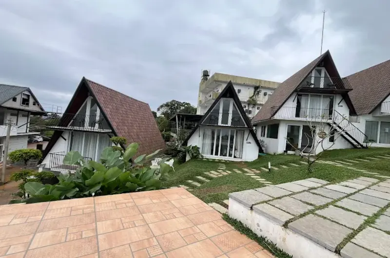 A-frame cottages and paved lawn pathways at Trip Mount resort in Vagamon