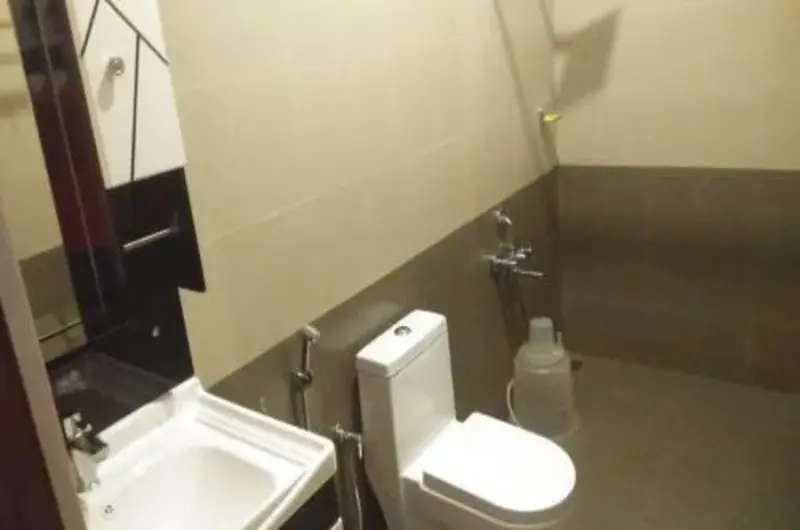 Clean modern attached bathroom interior with toilet and vanity sink at Thanal Farm Stay Vagamon
