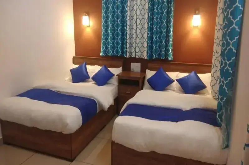 Spacious guest bedroom suite with two comfortable double beds and blue accent linens at Thanal Farm Stay Vagamon