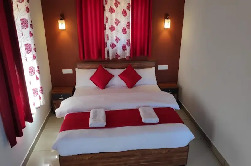 Cozy guest bedroom interior featuring comfortable beds and red accent bedding at Thanal Farm Stay Vagamon